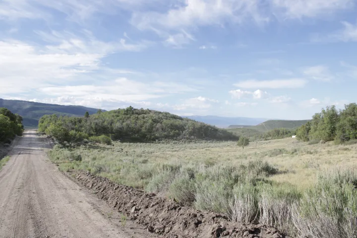 Unpaved road traversing a landscape with rolling hills and distant mountains