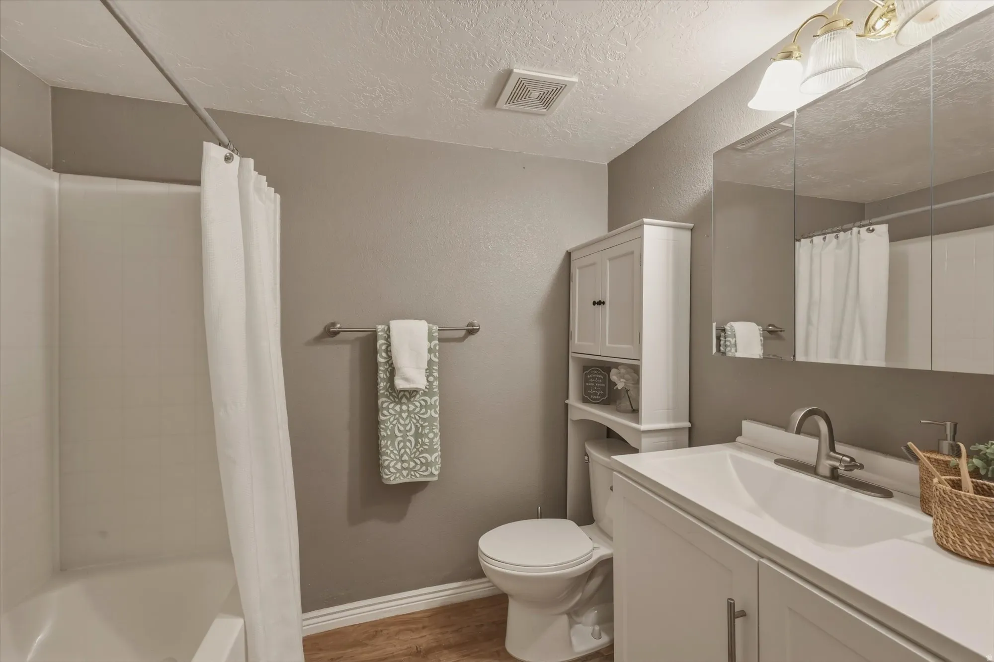 Bathroom with a single vanity, wood-finish flooring, and a shower-over-tub combination