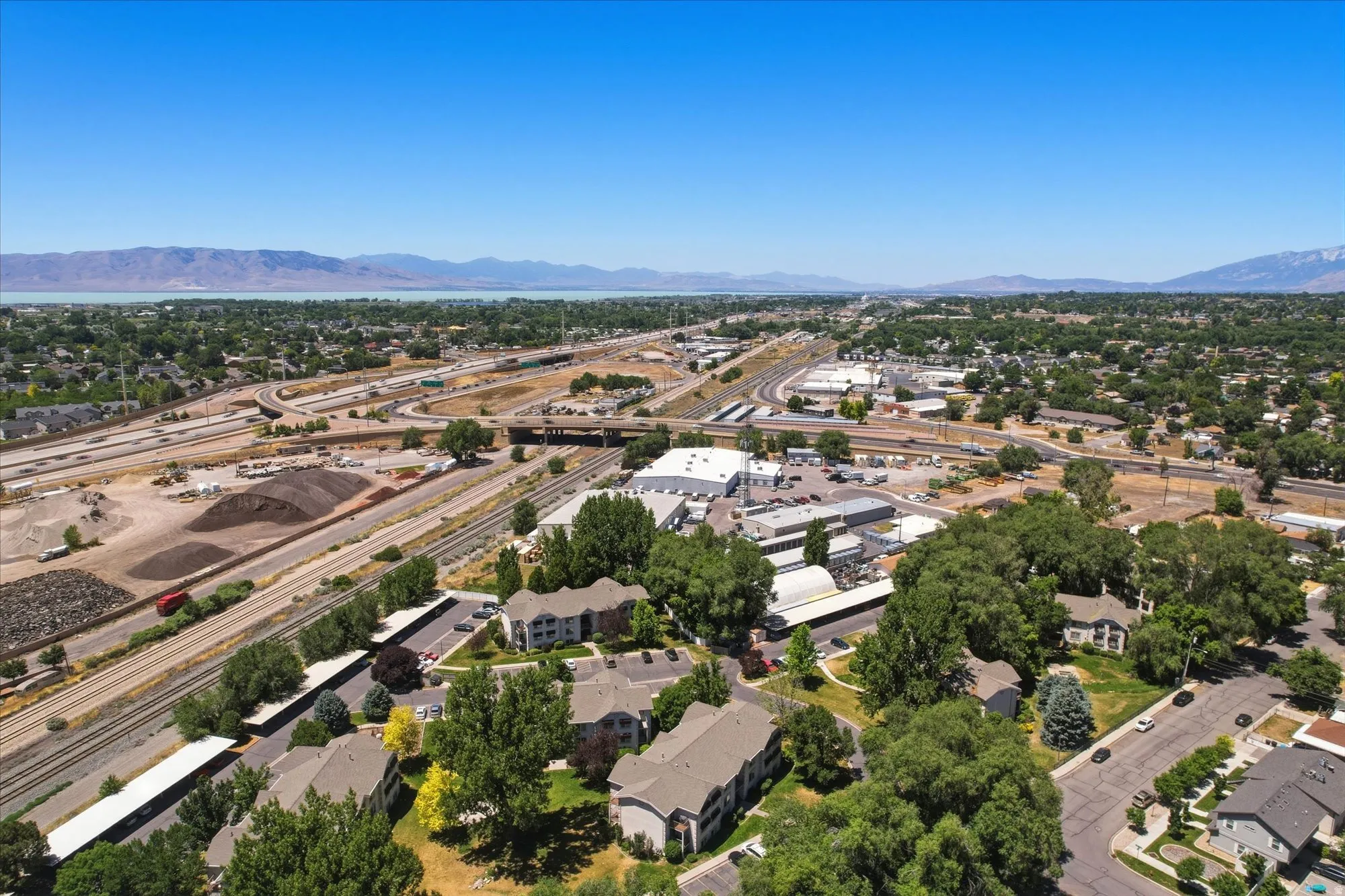 Expansive aerial perspective showcasing a vibrant community with diverse residential structures, extensive road networks, and abundant mature trees