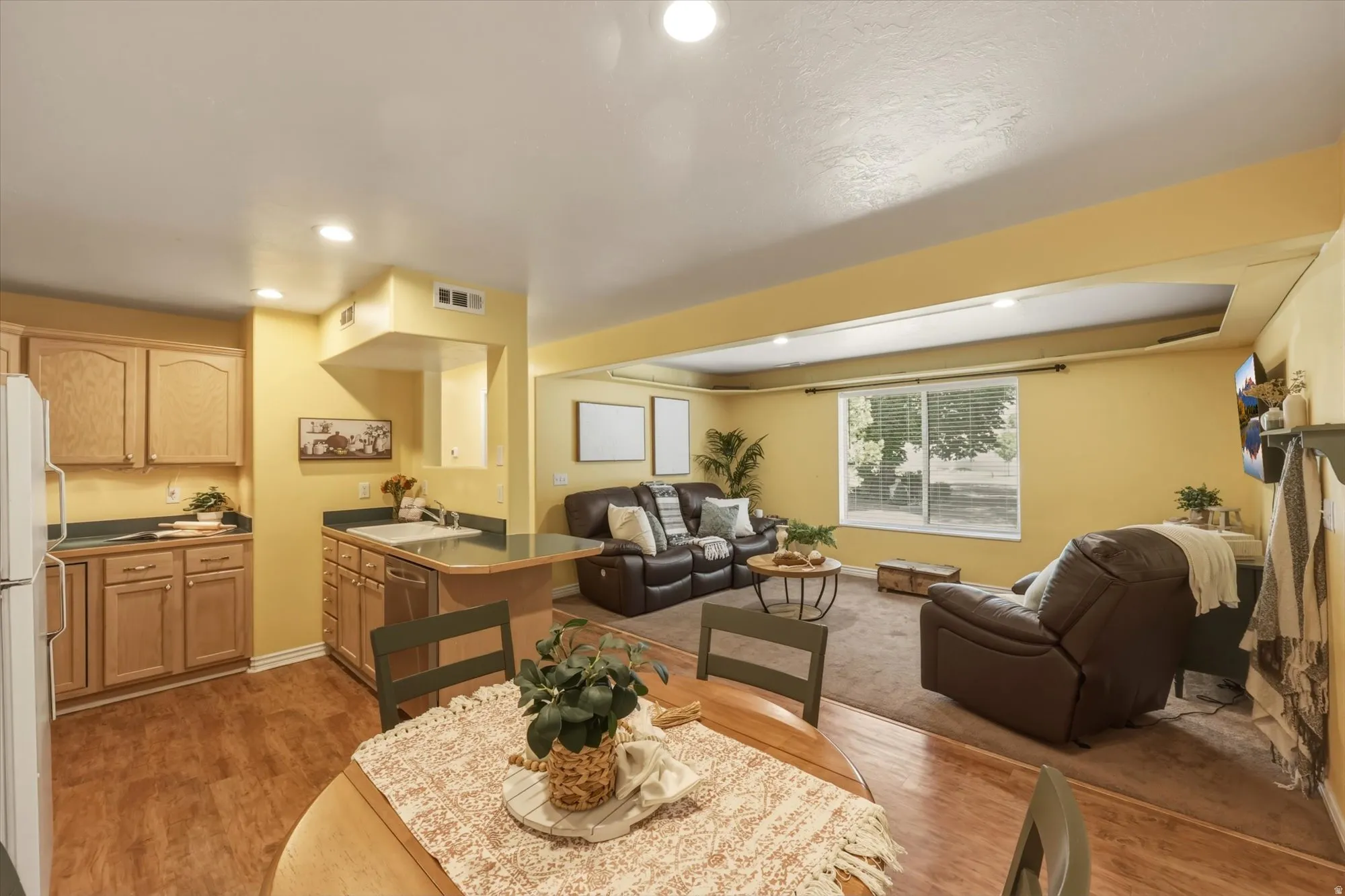 Open-concept living area featuring wood-finish flooring, recessed lighting, and a large window