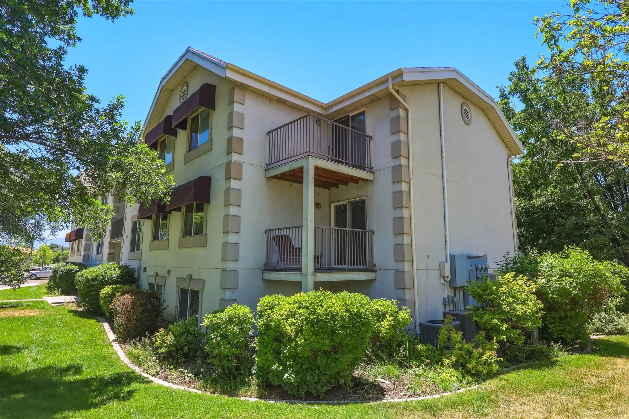 Multi-story building featuring light stucco siding, decorative stone-look trim, and multiple balconies with metal railings