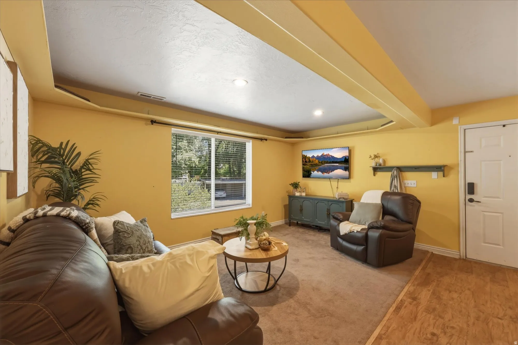 Living area featuring recessed lighting, a large window, and wood-finish flooring transitioning to carpeting