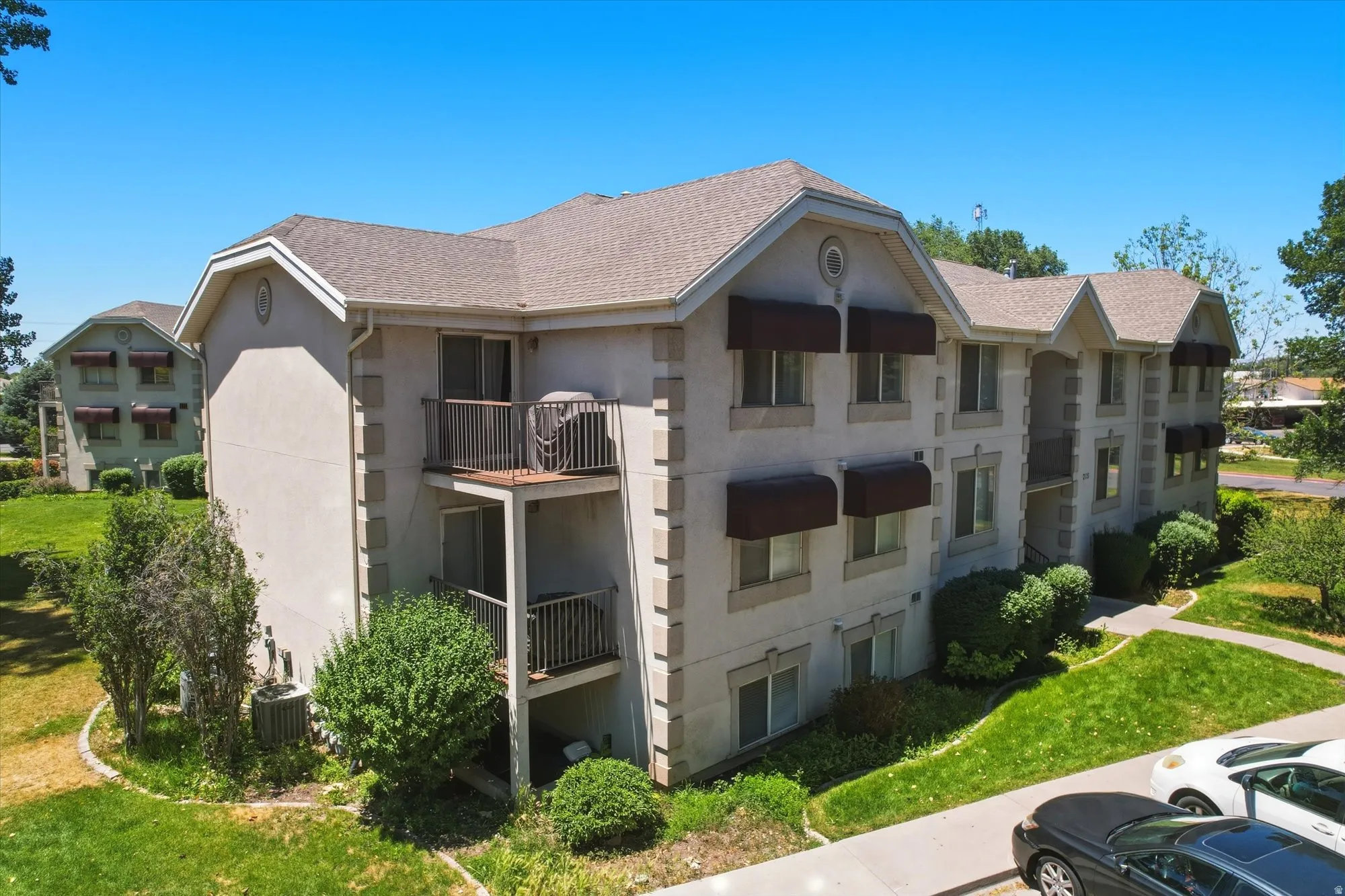 Multi-story building featuring light stucco exterior, gabled rooflines, and individual balconies