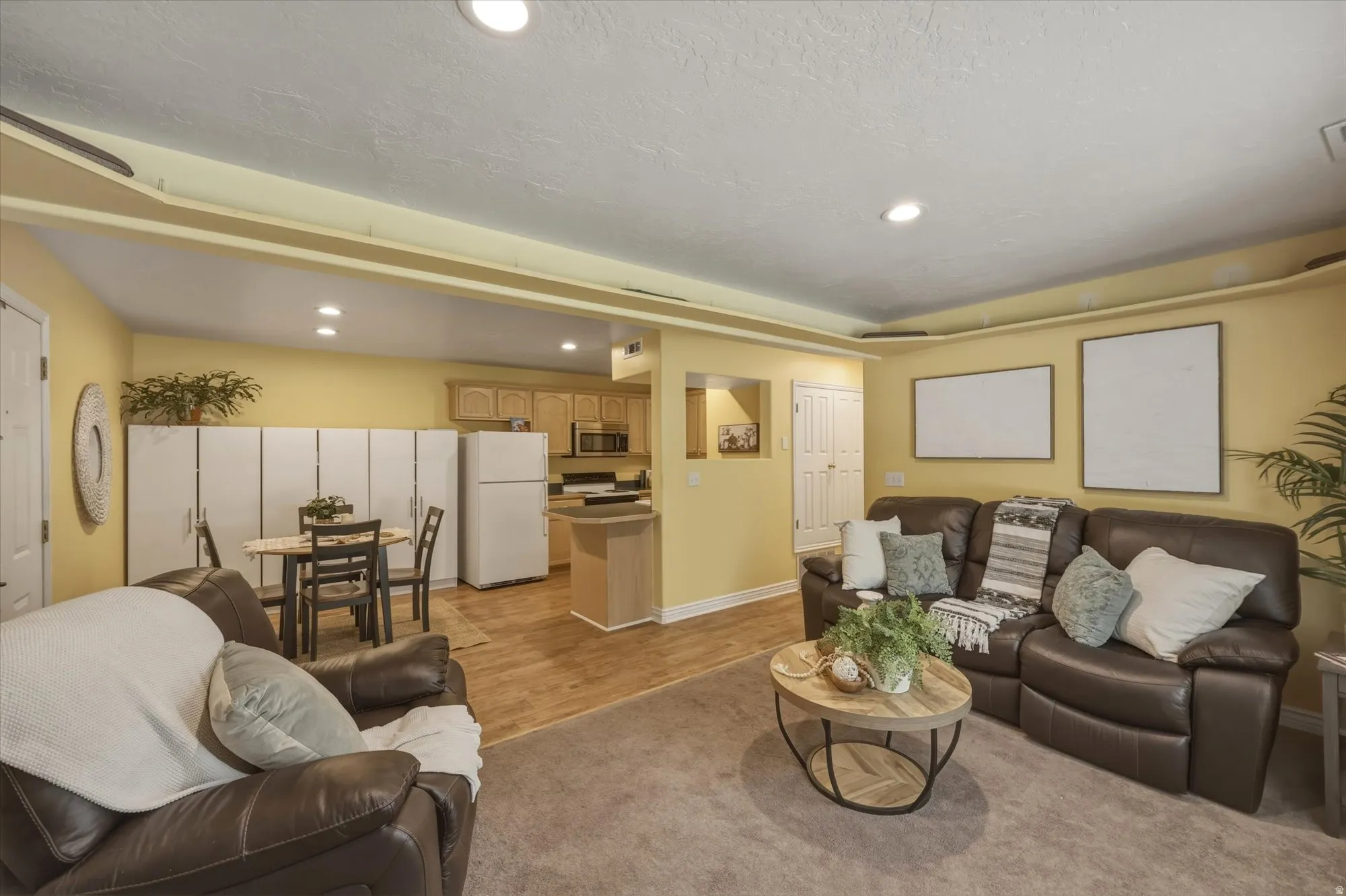 Open-concept living space featuring recessed lighting and a combination of carpet and wood-finish flooring