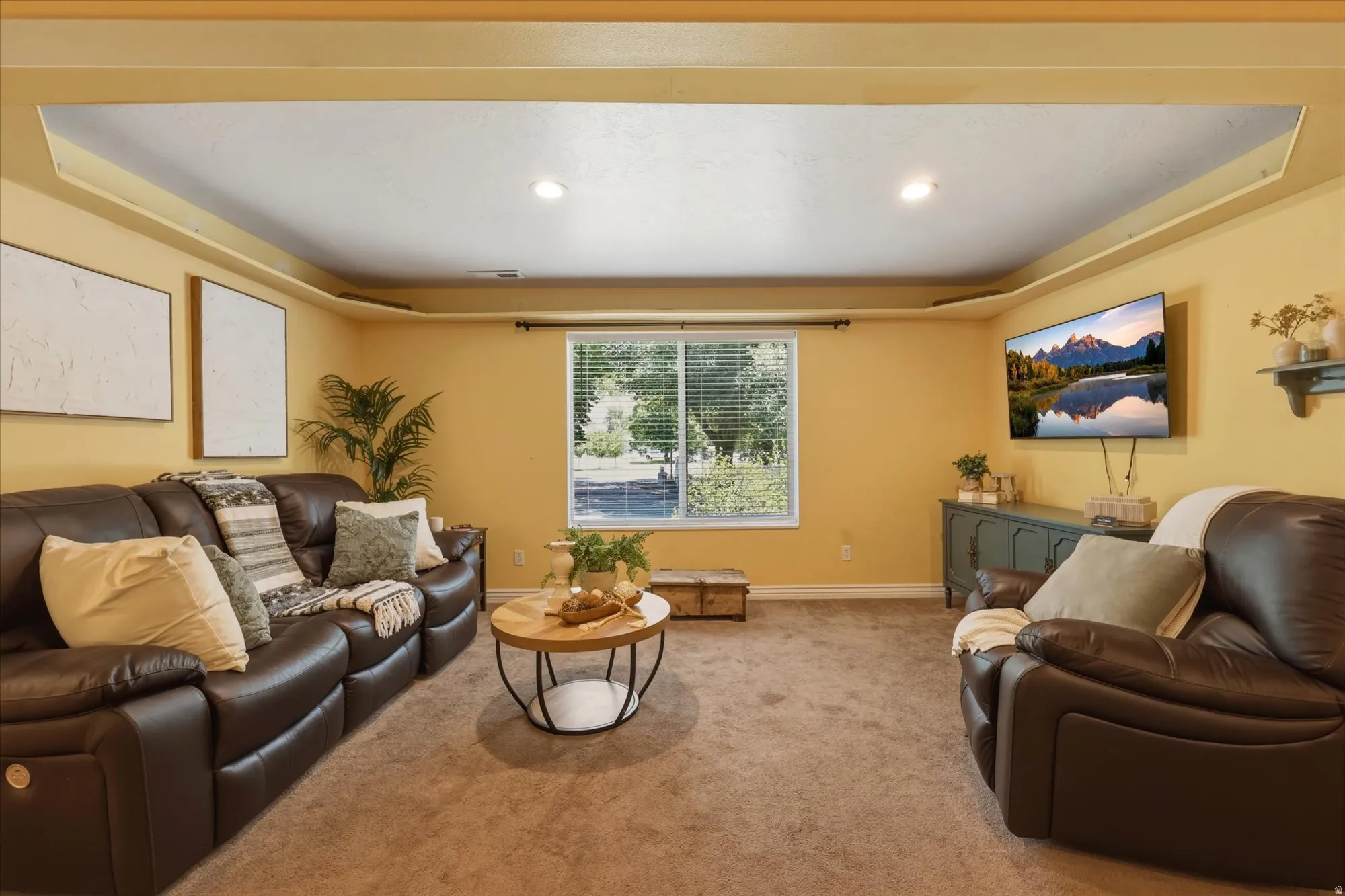 Recessed lighting illuminates a tray ceiling and warm-toned walls