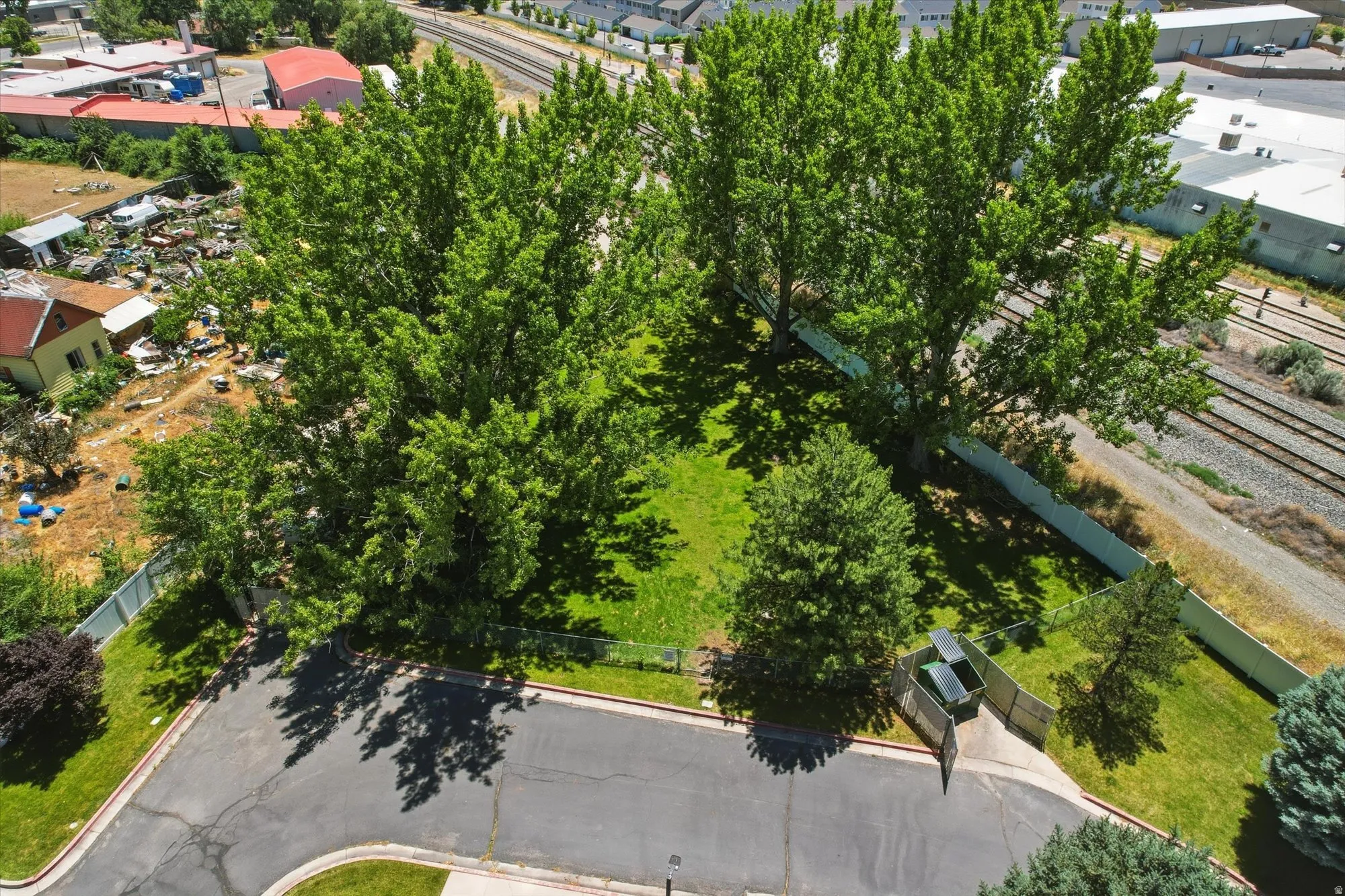 Expansive lot featuring mature trees, a manicured lawn, and paved street access