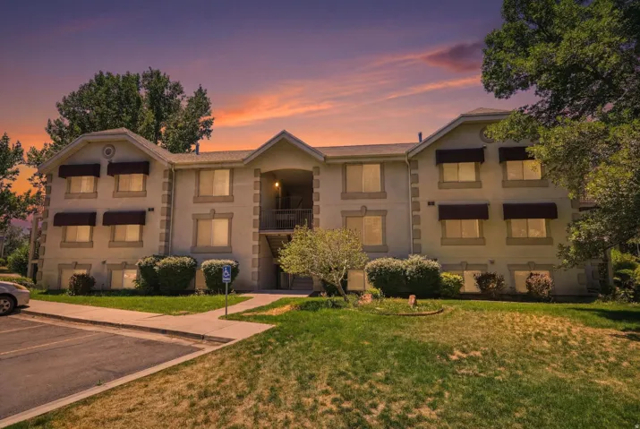 Multi-story stucco exterior featuring multiple windows with awnings, a central entryway, and an external staircase