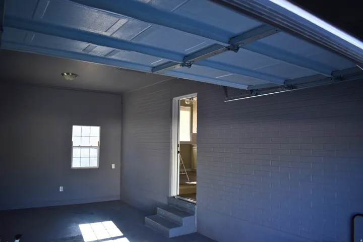 Garage space featuring painted brick walls, a multi-pane window, and a light fixture