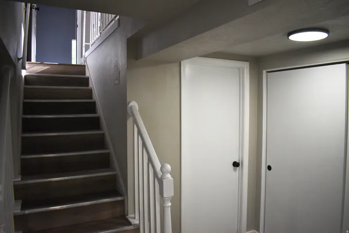 Staircase featuring wood-finish treads and white risers, complete with a white baluster railing