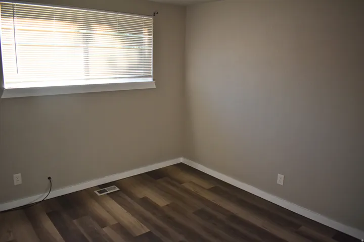 Room featuring wood-finish flooring, neutral wall paint, and white baseboards