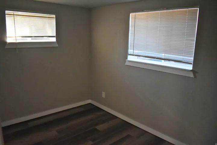 Interior room featuring wood-finish flooring, light-toned walls, and two windows with blinds