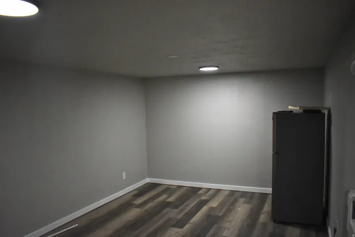 Interior space with wood-finish flooring, light gray walls, white baseboards, and recessed ceiling lighting