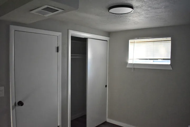 Room featuring a window with blinds, a ceiling-mounted light fixture, and two white doors