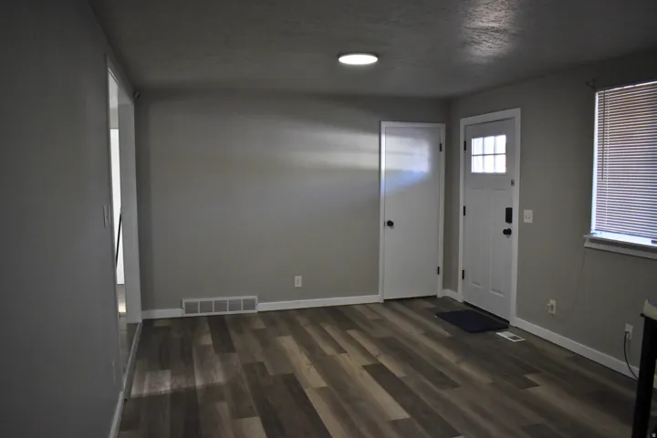 Spacious room featuring wood-finish flooring, light gray wall paint, and white baseboards