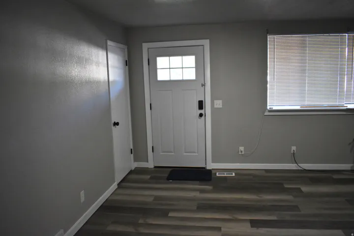 Entryway featuring wood-finish flooring, a white paneled door with multi-pane window inserts, and light gray painted walls