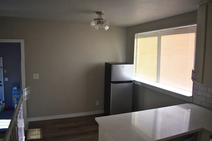 Kitchen area featuring a window with horizontal blinds, a white countertop, and white subway tile backsplash