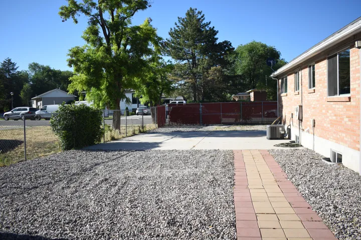 Expansive gravel yard with a concrete patio area and a decorative paver pathway