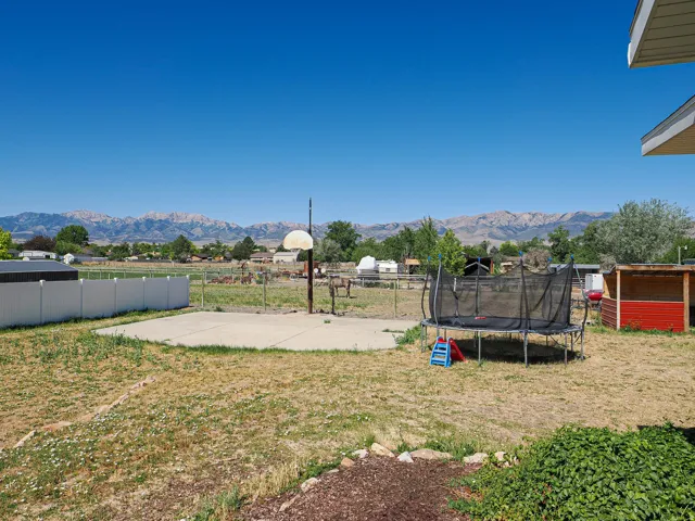 Expansive grassy yard with a concrete pad and distant mountain scenery