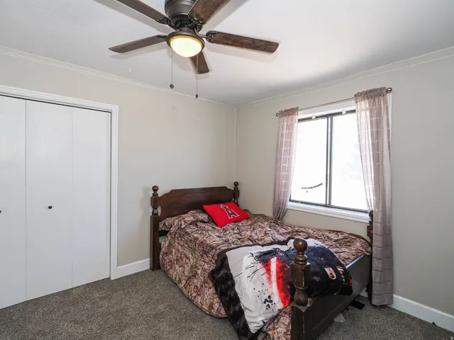Room featuring light-toned walls, crown molding, and a ceiling fan with integrated lighting