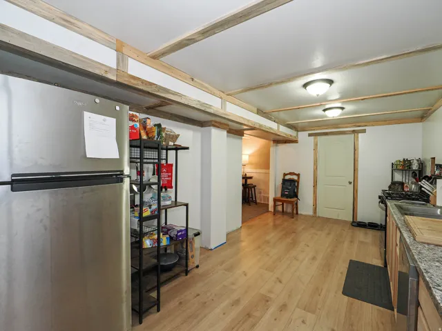 Open-concept kitchen with wood-finish flooring, white walls, and a wood-beamed ceiling