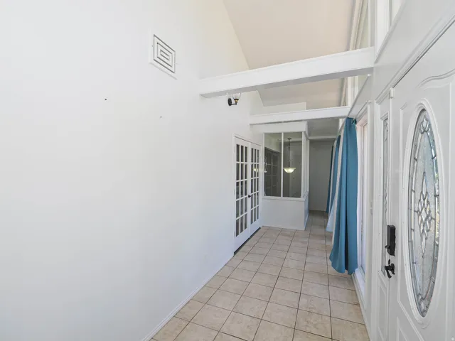 Entryway featuring a decorative leaded glass front door, vaulted ceiling, and ceramic tile flooring