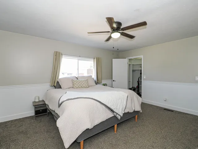 Bedroom featuring neutral wall paint, white wainscoting, and carpet flooring