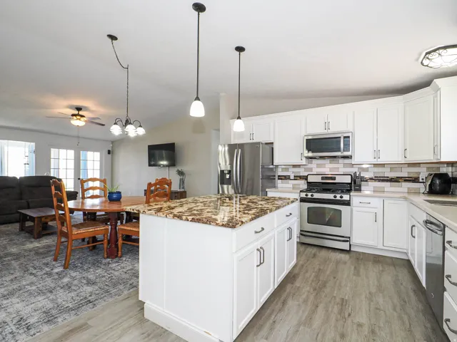 Kitchen featuring a central island with a speckled countertop, white cabinetry, and stainless steel appliances