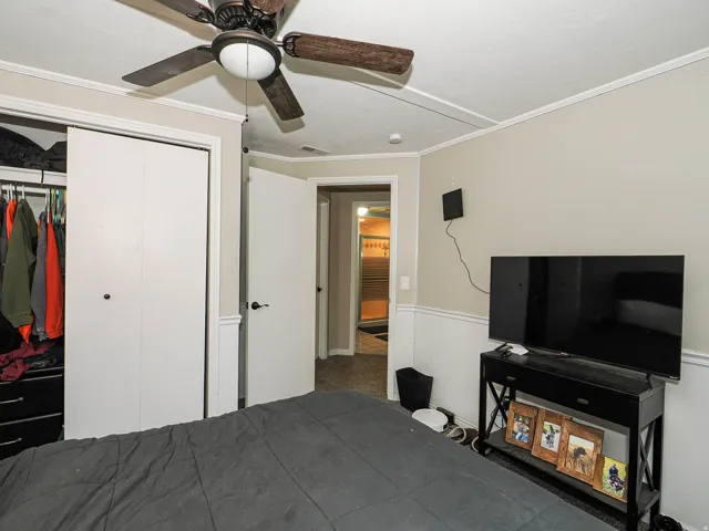 Bedroom with crown molding, chair rail molding, and a ceiling fan with integrated lighting