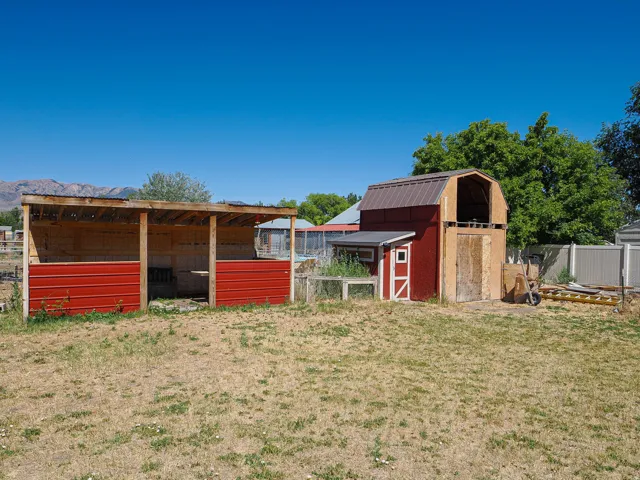 Two outbuildings featuring a red barn-style shed with a gambrel roof and an open-sided structure with a corrugated metal roof