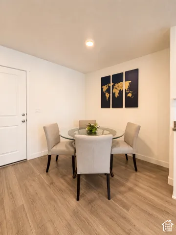 Bright interior space featuring wood-finish flooring, white baseboards, and a white interior door with a round knob