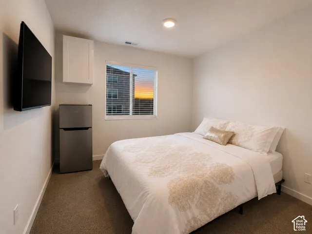 Bedroom featuring carpeted flooring and a window with horizontal blinds