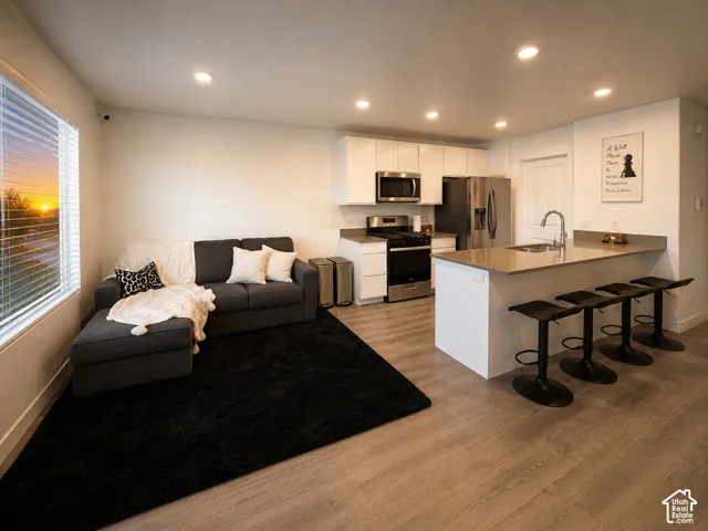 Open-concept living space featuring wood-finish flooring, recessed lighting, and a large window with blinds