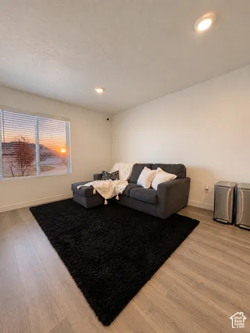 Spacious room featuring wood-finish flooring, recessed lighting, and a large window with blinds