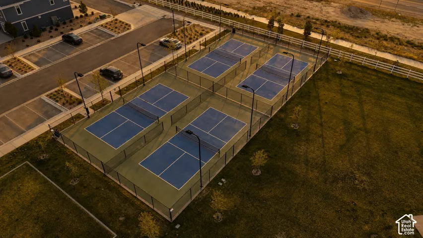 Four outdoor courts featuring blue playing surfaces, perimeter fencing, and integrated lighting