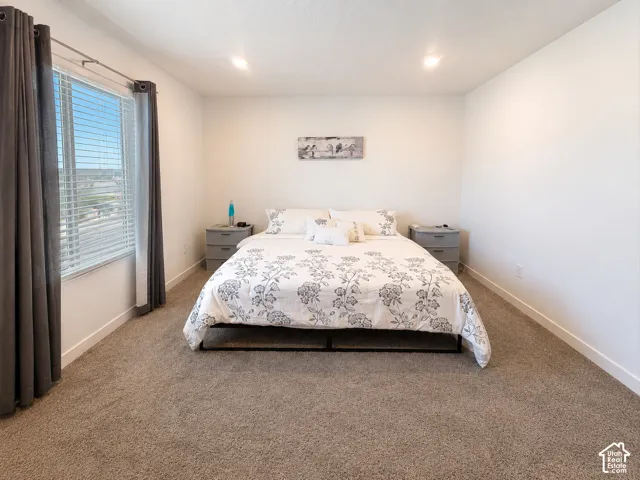 Spacious bedroom featuring neutral carpeting and white baseboards