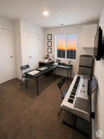 Bright room featuring a window with horizontal blinds, neutral-toned carpet flooring, a recessed ceiling light, and a white wall-mounted cabinet