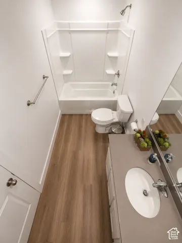 Full bathroom featuring a white tub and shower combination with integrated shelving, a polished chrome showerhead, and a matching chrome grab bar
