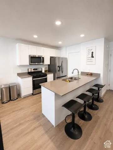 Modern kitchen featuring white cabinetry, stainless steel appliances, and a light-toned countertop