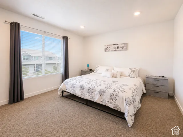 Carpeted room featuring a large window with blinds and dark-toned curtains, recessed lighting, and white baseboards