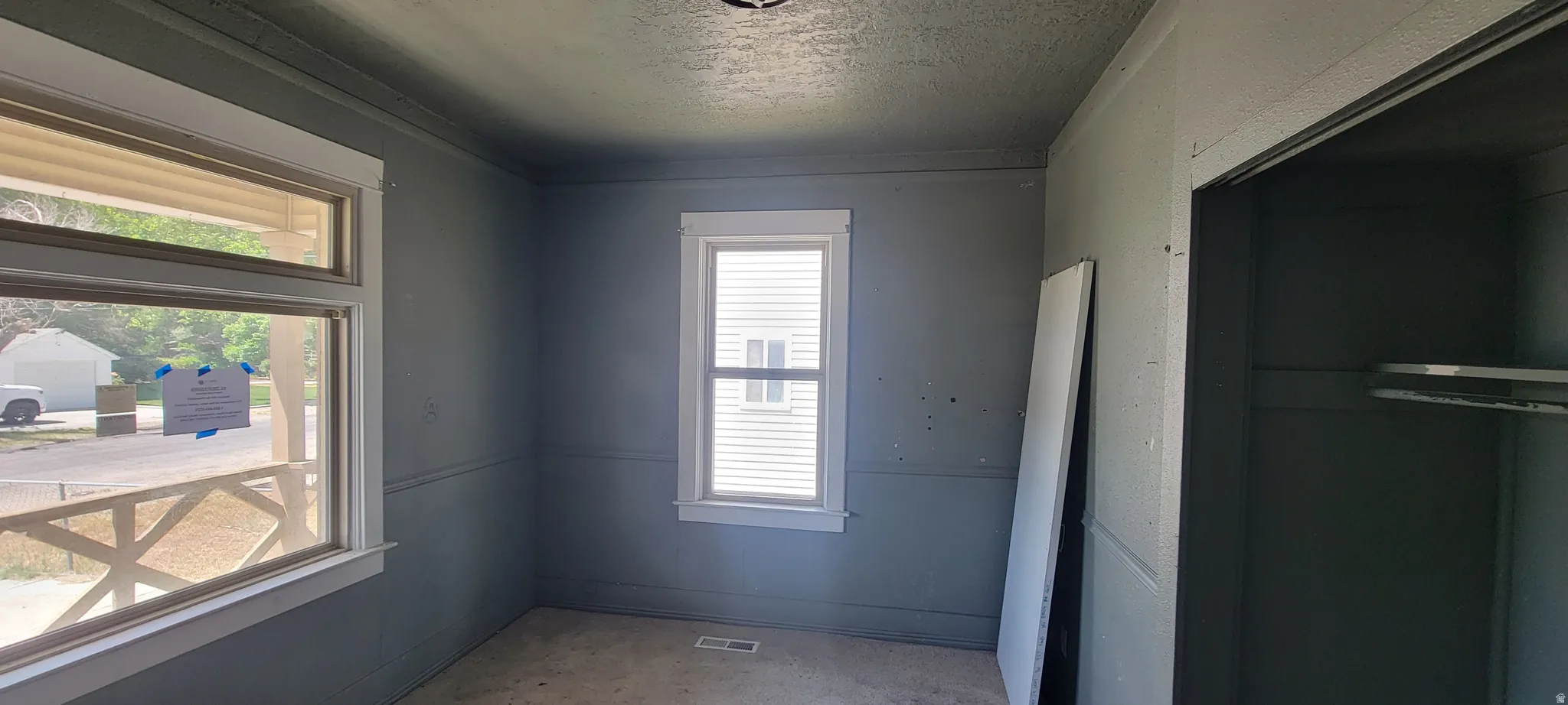 Room featuring multiple windows with white trim, gray painted walls with chair rail detailing, and a ceiling-mounted light fixture