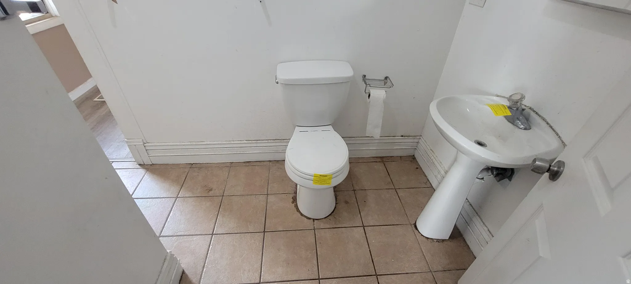 Restroom with ceramic tile flooring, a white pedestal sink, and a white two-piece toilet