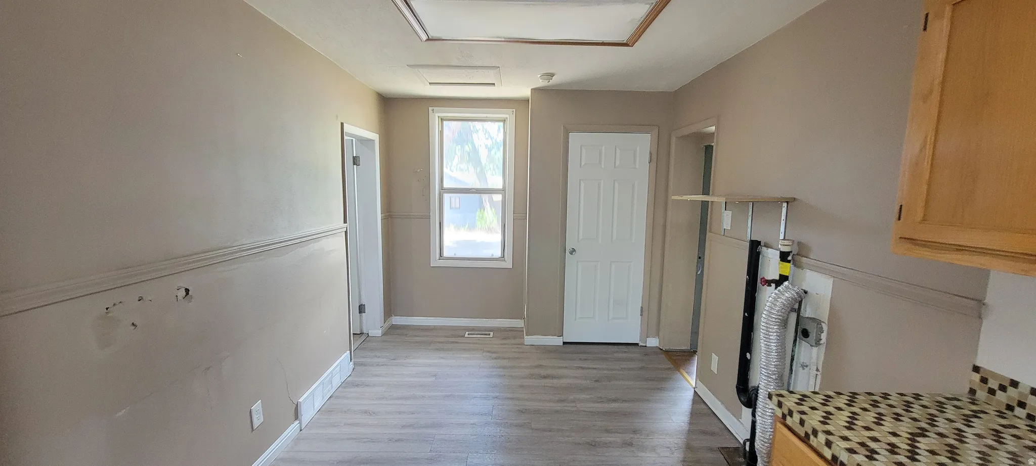 Neutral tone walls featuring chair rail molding, wood-finish flooring, and white trim throughout