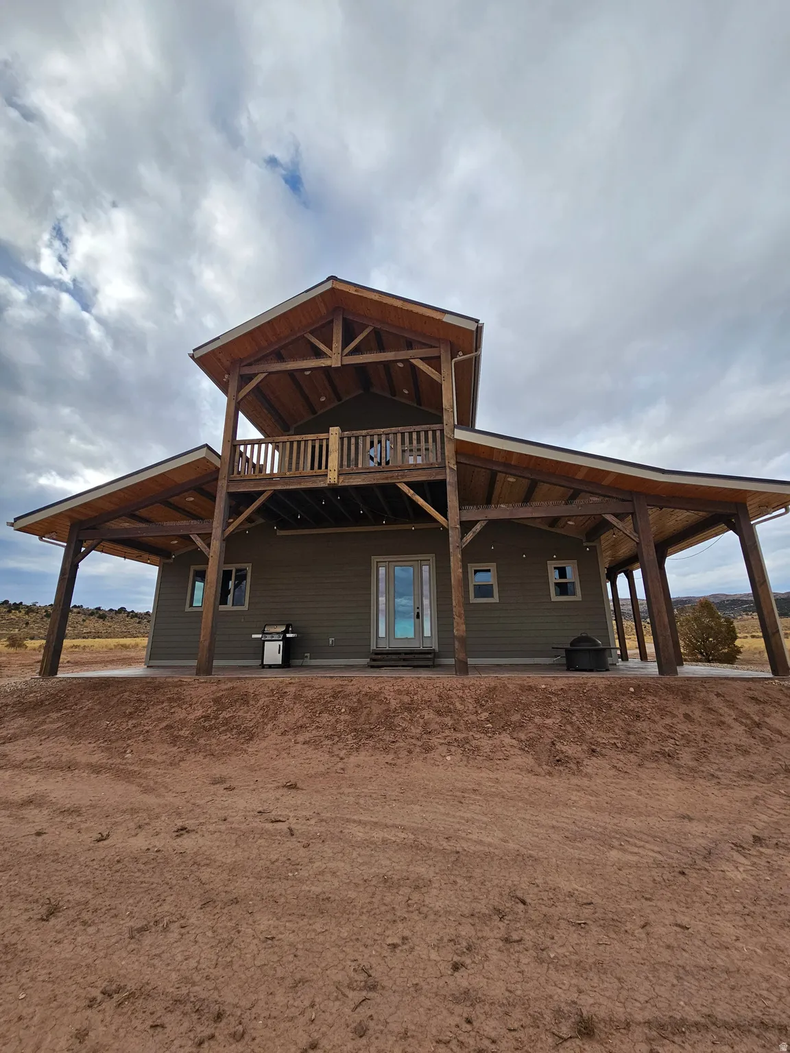 Two-story residence featuring a covered patio, upper-level balconies, and exposed wood beam construction