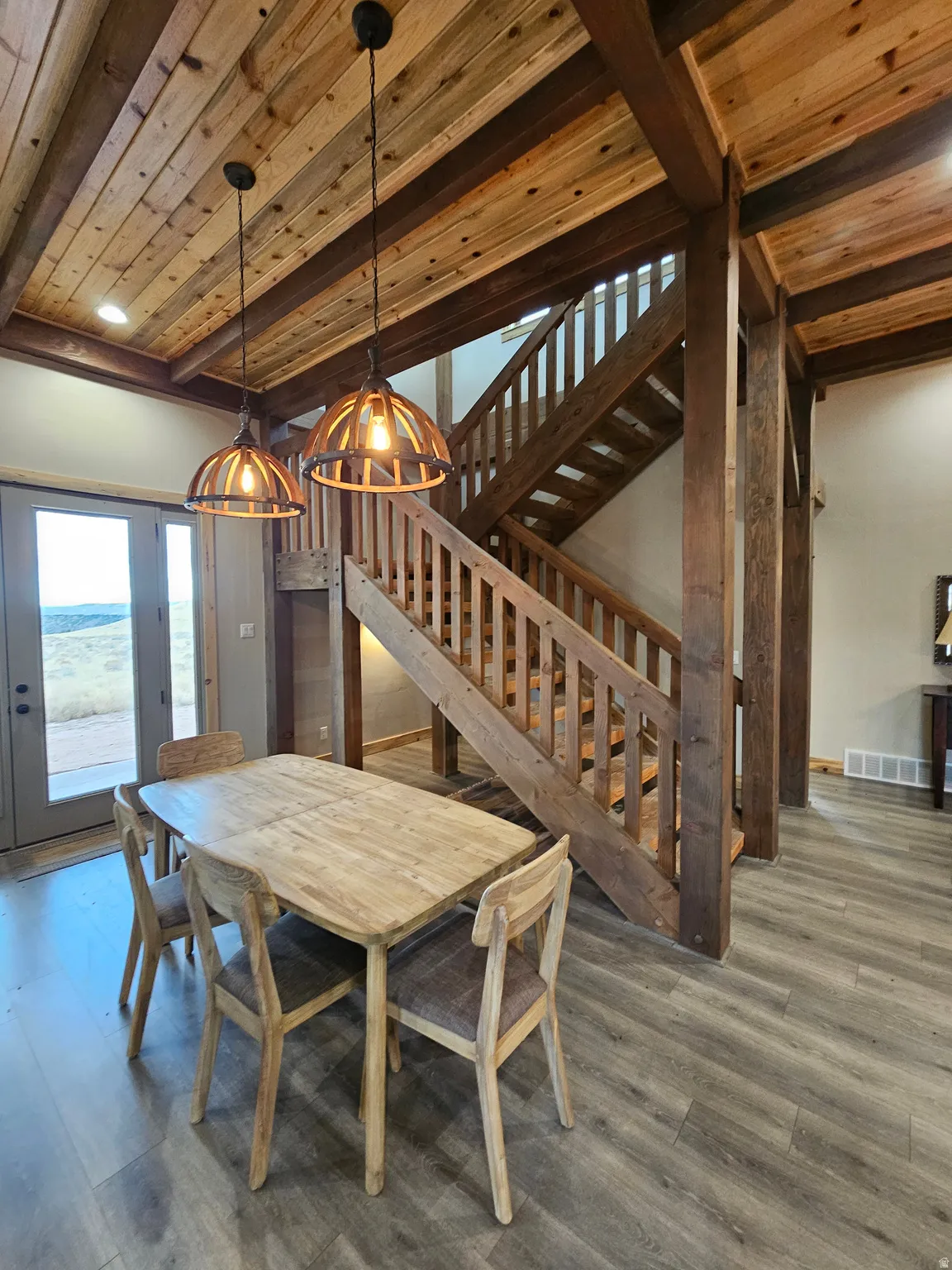 Exposed wood beam ceiling and staircase, featuring two distinct pendant light fixtures