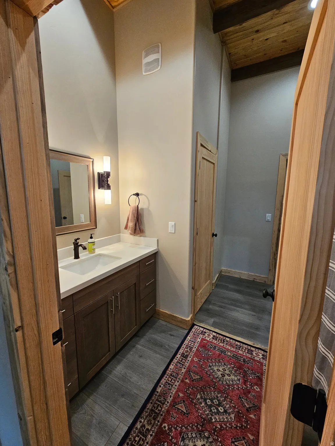 Bathroom & vanity featuring a quartz countertop, integrated sink, and dark wood cabinetry