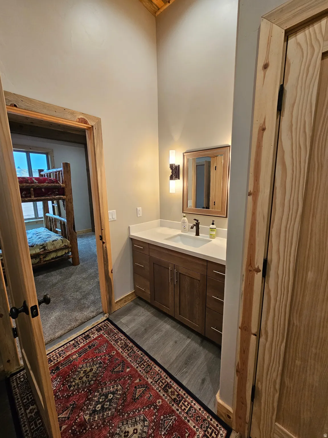Bathroom downstairs with wood-finish flooring and a light wood vanity featuring a white countertop and integrated sink