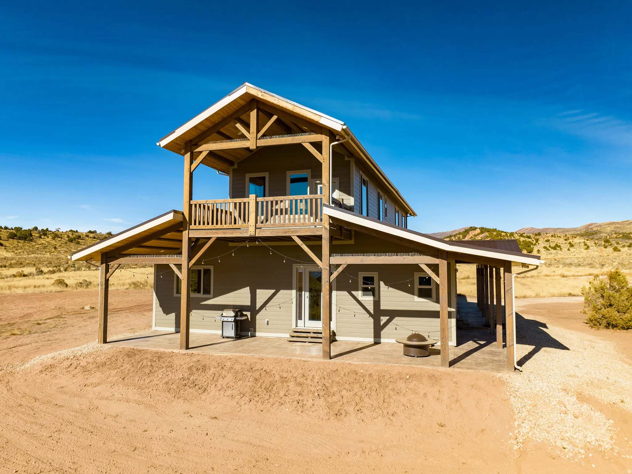 Two-story residence featuring a covered patio, upper-level balconies, and exposed wood beam construction