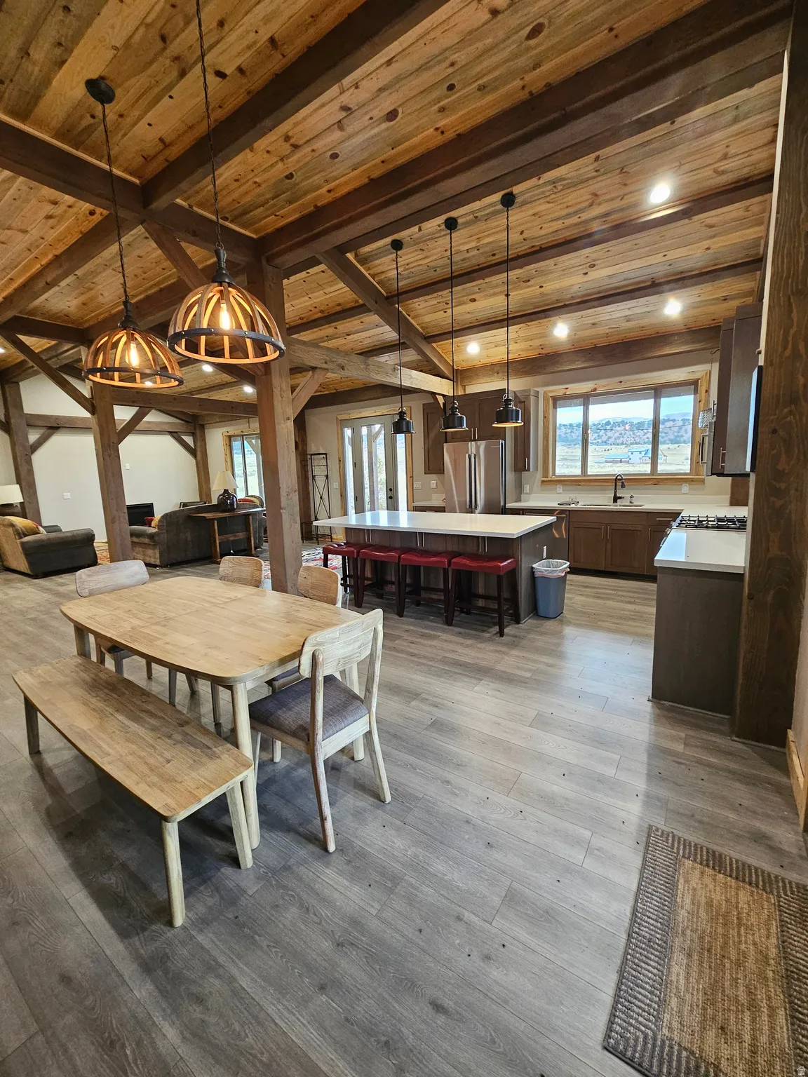 Open-concept living space featuring wood-finish flooring, exposed timber beams
