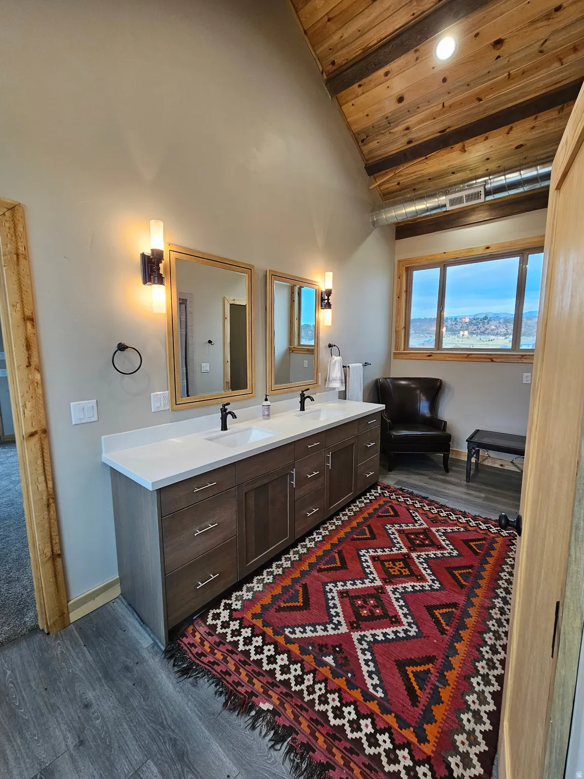 Master Bathroom featuring a double vanity with matte black faucets, wood-finish flooring, a vaulted wood-plank ceiling, and a window providing natural light