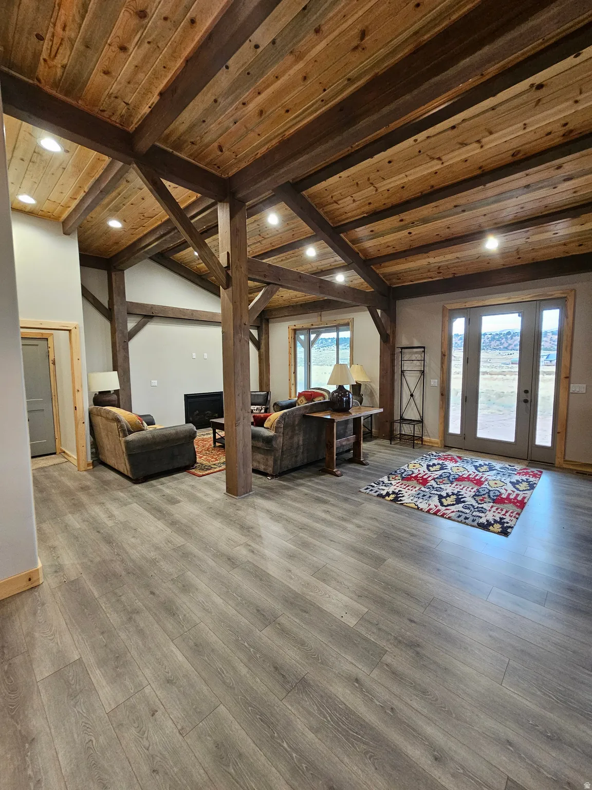 Open living space featuring wood-finish flooring and exposed wood beams & fireplace